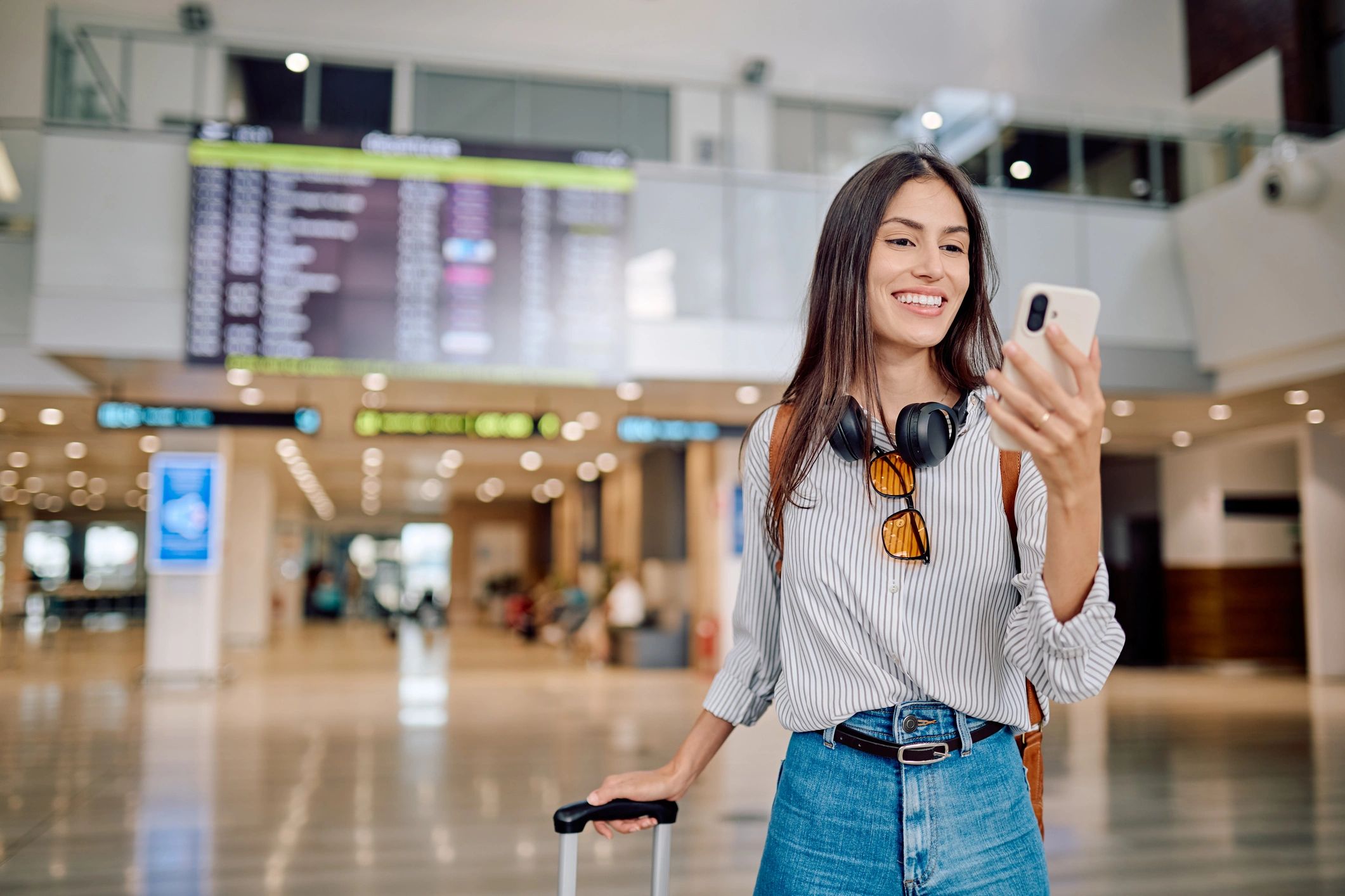 Viajera usando su móvil en el aeropuerto